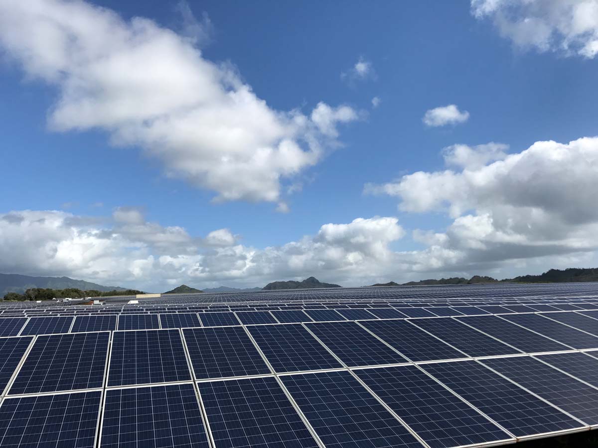 hundreds of solar panels with clouds and a beautiful blue sky