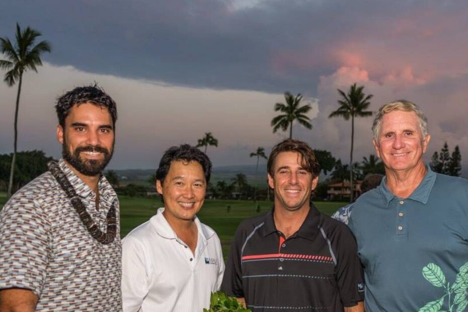 four men standing at the golf course with palm trees and clouds in background