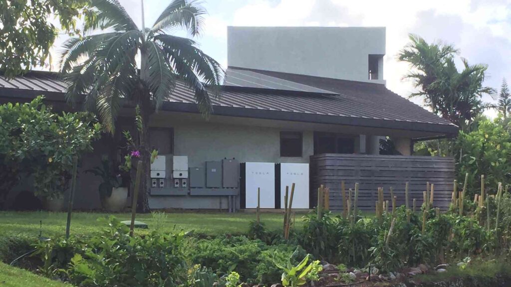 tesla solar panels and tesla power wall on a home in hawaii with garden