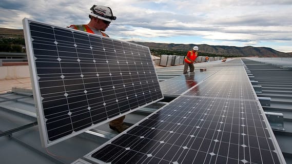 Two Rising Sun Solar employees installing solar panels on a commercial building