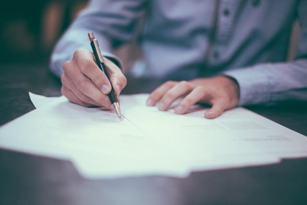 hands holding a pen signing a paper